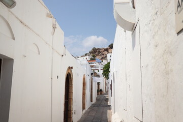 Narrow street in Lindos town on Rhodes island, Dodecanese, Greece. Beautiful scenic old ancient white houses