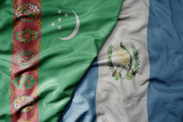 big waving national colorful flag of guatemala and national flag of turkmenistan.