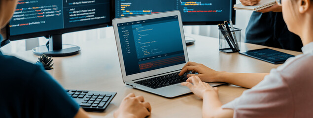 Cropped image of female web developer coding on laptop while computer displayed program and...