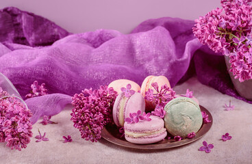 Sweet pastel french macaroons and lilac flowers on light gray background. Beautiful composition for bakery and pastry shop