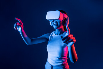 Smart female standing in cyberpunk neon light wear VR headset connecting metaverse, futuristic...