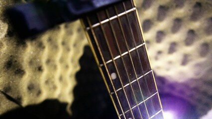 An acoustic guitar leaning against a soundproof studio wall. Playing guitar day.  Music studio: old...
