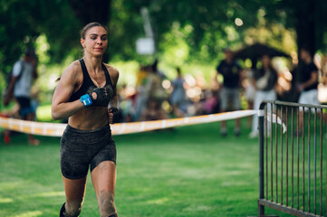 Woman participating in an obstacle course race while running to the finish line