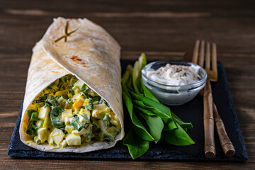 Homemade burrito wraps with boiled eggs, green wild garlic and sour cream for healthy breakfast on...