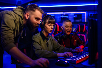Woman esport gamer playing video games while her friends are sitting next to her