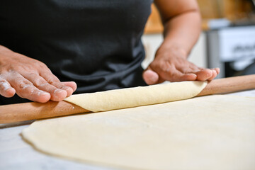 person rolling dough with rolling pin