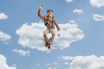 Obraz premium Male pensioner sitting on a cloud and waving