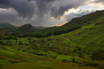 Fototapeta na wymiar AERIAL: Threatening rain clouds hover above rolling green hills of Lake District
