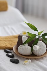 Fototapeta na wymiar Spa stones, flowers, towel and herbal bags on massage table indoors