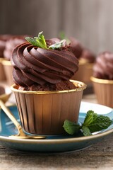 Delicious chocolate cupcake with mint on wooden table, closeup