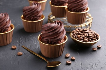 Delicious chocolate cupcakes and coffee beans on black textured table
