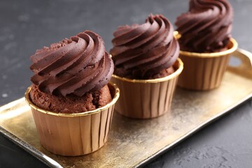 Delicious chocolate cupcakes on black textured table, closeup