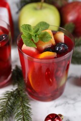 Aromatic Sangria drink in glass, ingredients and Christmas decor on white marble table
