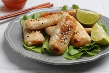 Tasty fried spring rolls served on light table, closeup