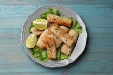 Tasty fried spring rolls on light blue wooden table, top view