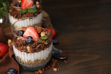 Tasty granola with berries, nuts, yogurt and chia seeds on wooden table, space for text