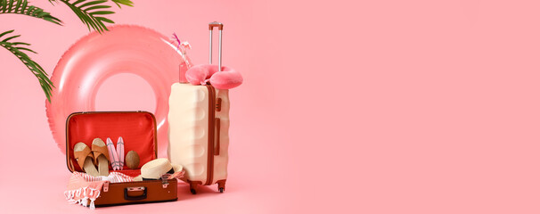 Suitcases with inflatable ring and beach accessories on pink background. Travel concept