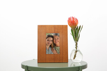 Family portrait of mother and daughter in photo frame on table against white background