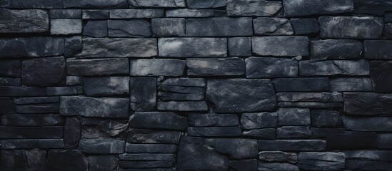 A detailed view of a solid black stone wall set against a plain black backdrop