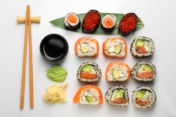 Set of delicious sushi rolls on white background, flat lay
