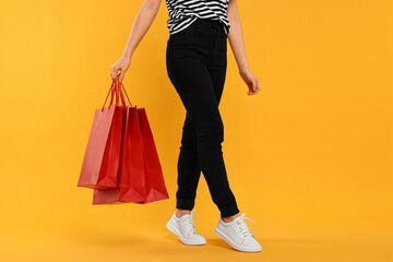 Woman with shopping bags on yellow background, closeup