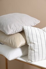 Fototapeta na wymiar Soft pillows on table near beige wall