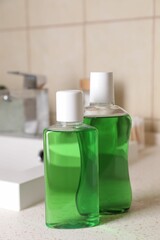 Fresh mouthwashes in bottles on countertop in bathroom, closeup