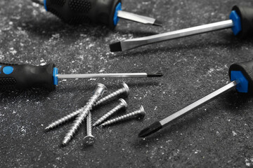 Set of screwdrivers and screws on grey table, closeup