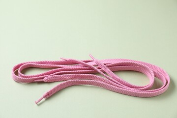 Stylish pink shoe laces on light olive background, closeup