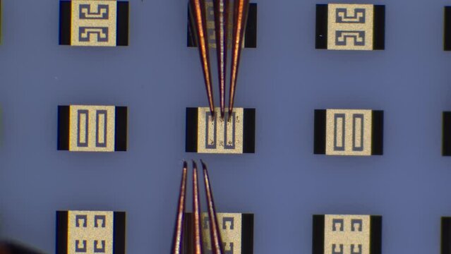 Radio frequency probe touchdown and manipulation on calibration substrate at microchip probing station. Microscope view. 