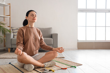 Beautiful woman meditating on mat at home