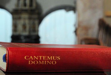 Antique red leather book with religious songs Cantemus Domino (Let us sing to the Lord) on church...