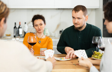 Men and women play card game poker during friendly gatherings at home. Couple enthusiastically...