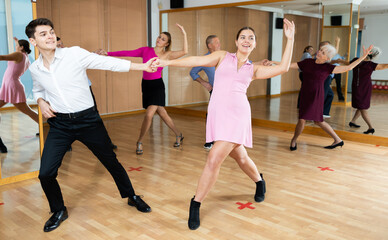 Dynamic young pair engaging in ballroom dance in dance studio. Pairs training ballroom dance in hall