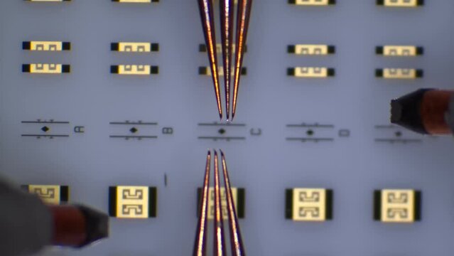 Radio frequency probe touchdown and manipulation on calibration substrate at microchip probing station. Microscope view. 