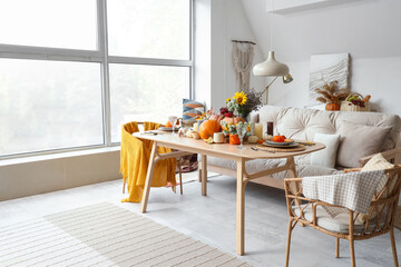 Dining table with autumn setting and pumpkins in room