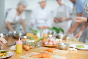 Row piece of salmon on wooden cutting board against blurred background of kitchen table of cooking...