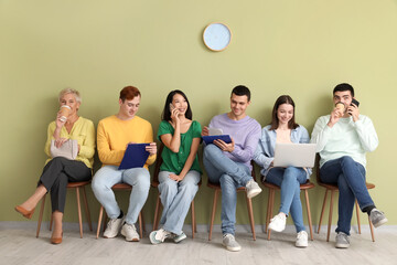 Obraz premium Applicants waiting for job interview near green wall in room