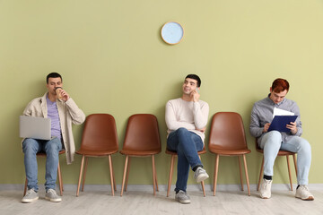 Obraz premium Male applicants waiting for job interview near green wall in room
