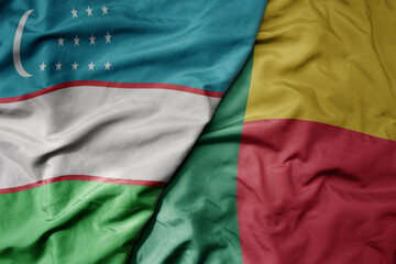 big waving national colorful flag of benin and national flag of uzbekistan.