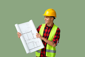 Young male engineer with blueprint on green background