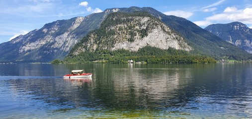 A motorboat sailing on the Hallstätter See lake. Mountain and forest in the background. Blue sky. Hallstatt, Austria.