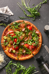 Delicious pizza with tomatoes and arugula on black background