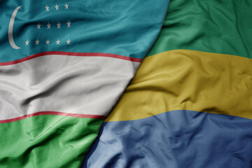 Fototapeta premium big waving national colorful flag of gabon and national flag of uzbekistan.
