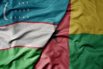 big waving national colorful flag of guinea bissau and national flag of uzbekistan.