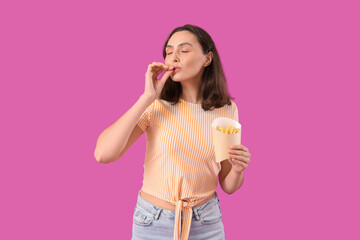 Beautiful young woman with french fries on purple background