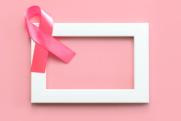 Top view of pink ribbon symbol of breast cancer on a white frame with space for text. Breast cancer awareness concept