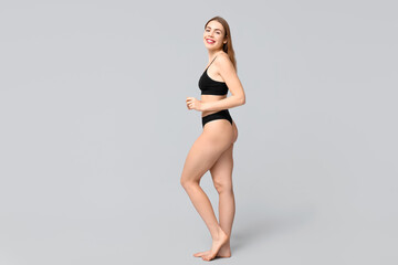 Pretty young woman in black cotton underwear on light background