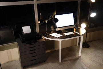 Interior of modern office with workplace, blank computer and glowing lamps