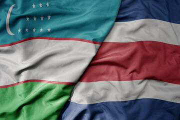 big waving national colorful flag of costa rica and national flag of uzbekistan.